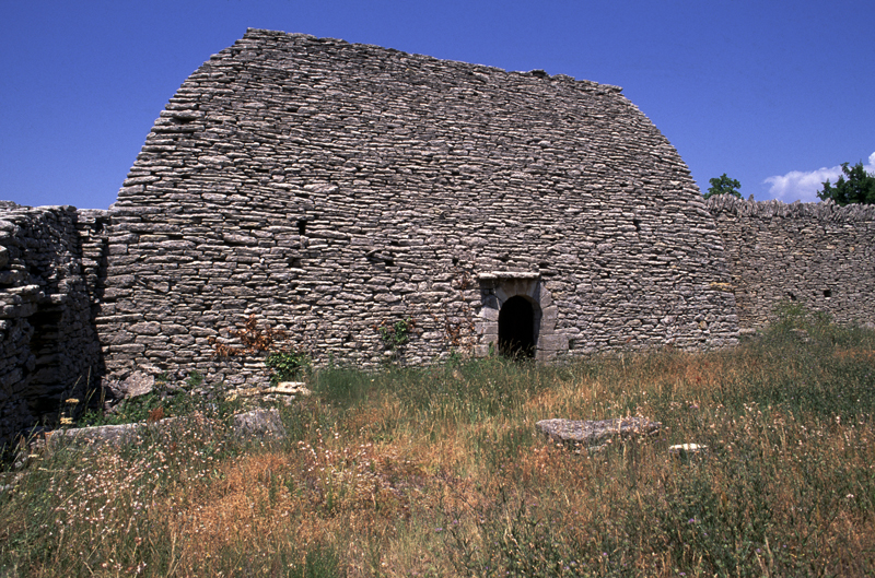 Gordes (Vaucluse) : ancienne grange-grenier en maçonnerie sèche, bâtie dans un enclos bordé de hauts murs renfermant une aire à dépiquer les céréales). Photo de Dominique Repérant.